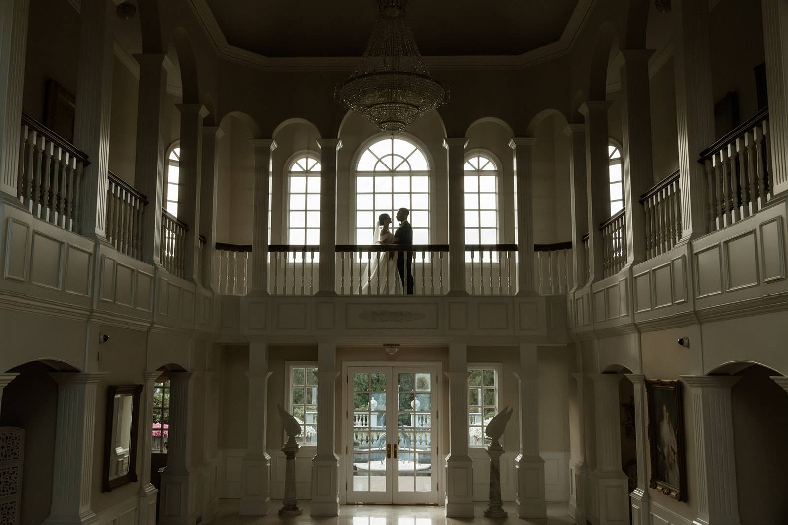 Bride and groom silhouetted on the balcony in the grand ballroom at chateau de michellia