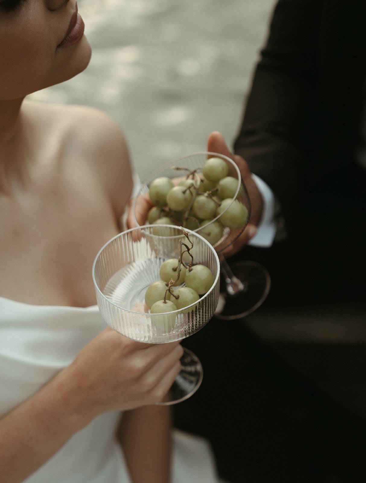 Bride and groom cheersing with coupe glasses filled with grapes